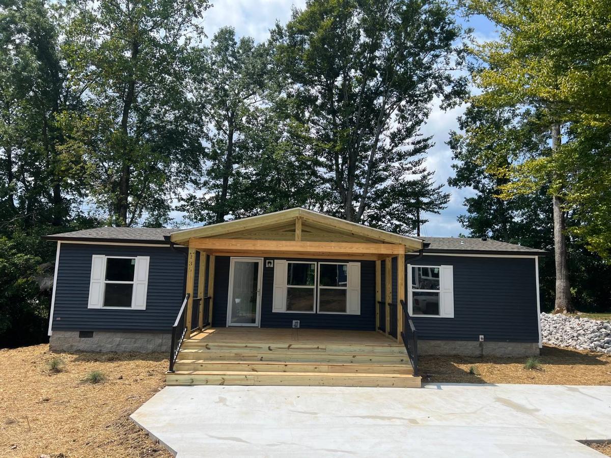 A new covered gable porch with wide steps and black metal railings on a navy house