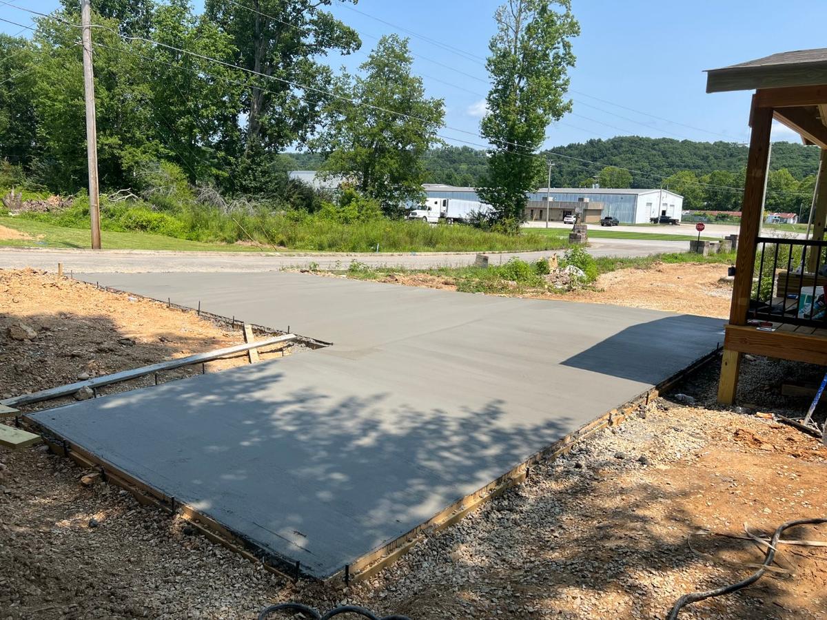A freshly poured concrete driveway leading to a new porch