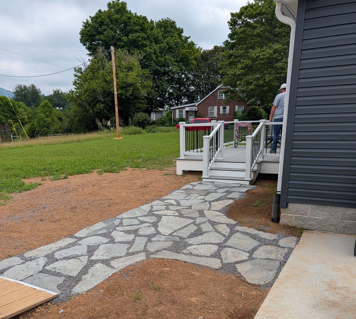 A natural flagstone walkway set in gravel, leading to the steps of a new deck with white railings