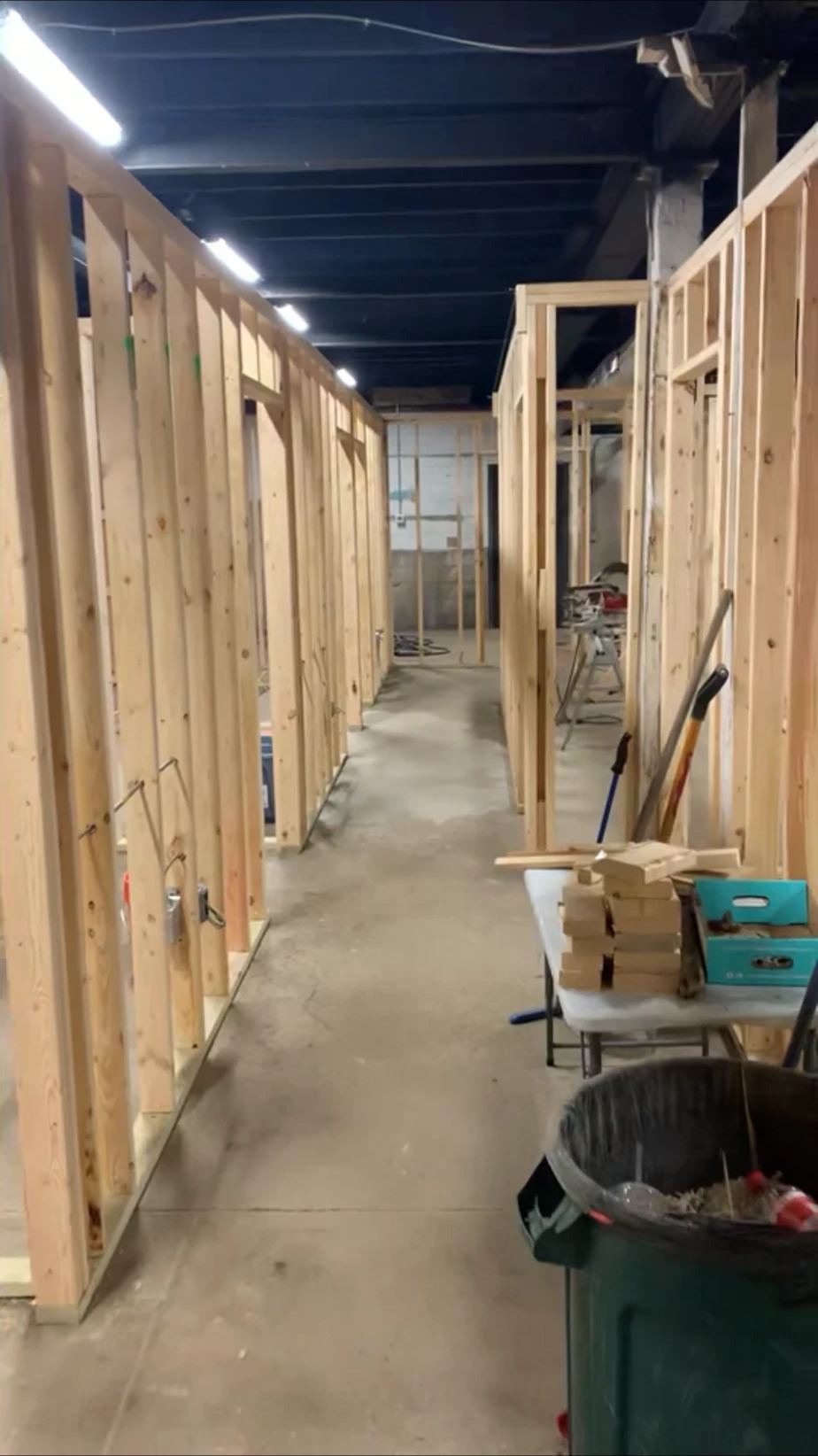 New stud walls and doorways framed down a long hallway in a basement build-out, with electrical boxes in place