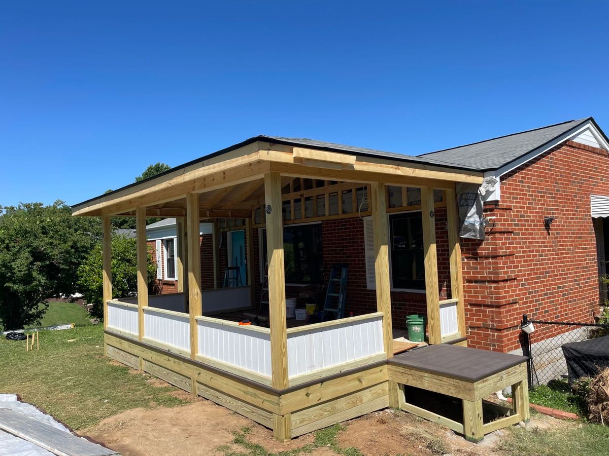 A new covered porch addition on a brick home, framed in pine with white paneled knee walls and a composite-topped step