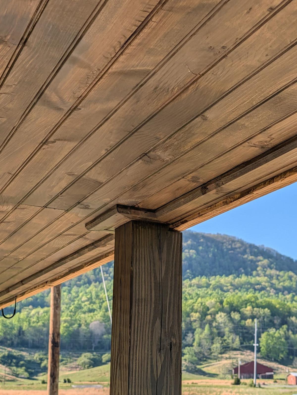 Stained tongue-and-groove porch ceiling and post, with a mountain view beyond