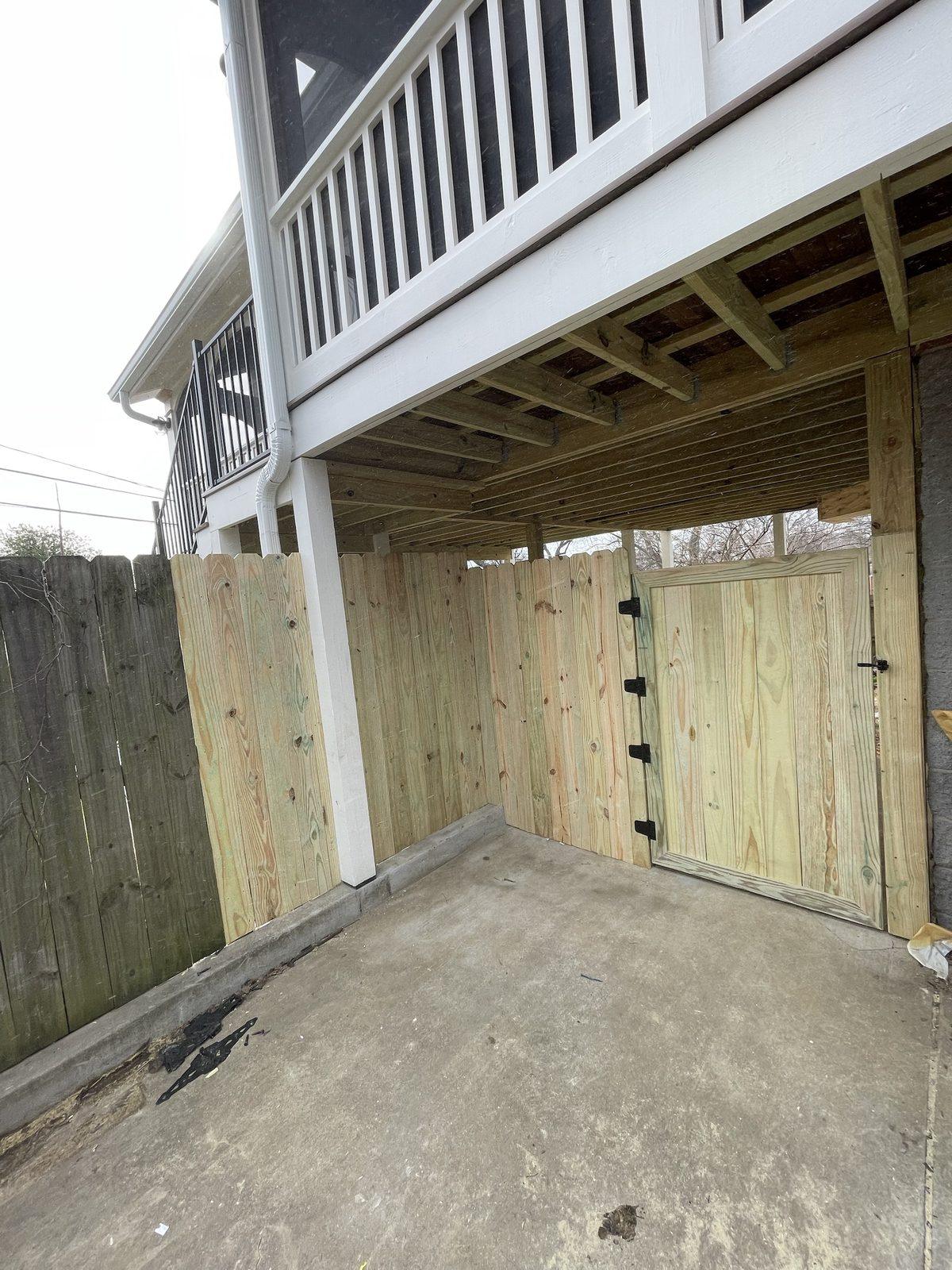 A new wood privacy fence and framed gate enclosing the space under a raised deck